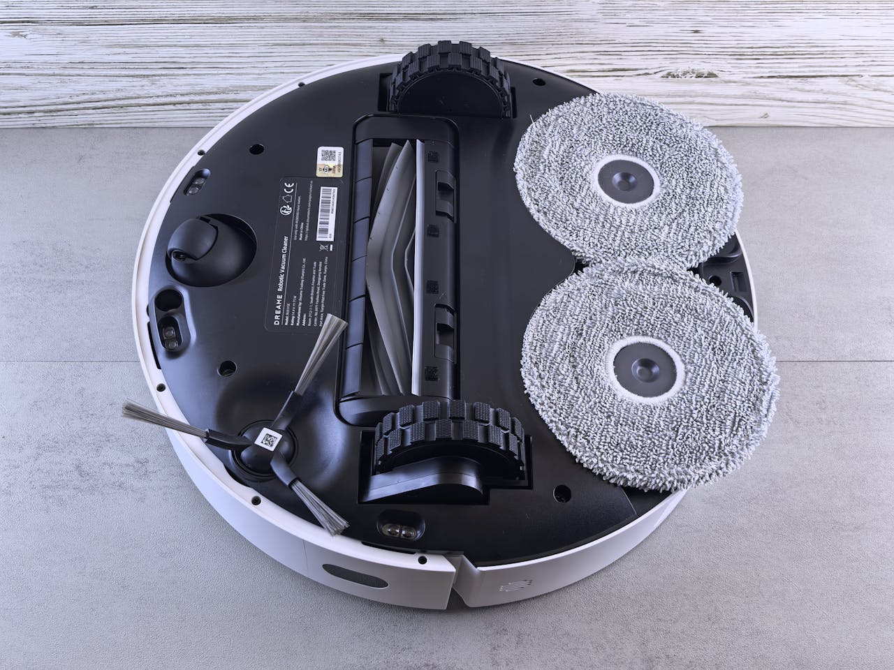 Home Detailed view of a robotic vacuum cleaner's underside showing brushes and wheels.